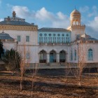 Proseguendo nel giardino appare una delle residenze del complesso, riconoscibile per logge, finestre azzurre e forme che accostano tradizione uzbeka e gusto europeo dell’epoca.