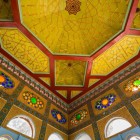 La visita si conclude osservando un soffitto dai vivaci pannelli geometrici locali e dalle vetrate policrome, sintesi dell’incontro tra artigianato uzbeko e influenze europee.